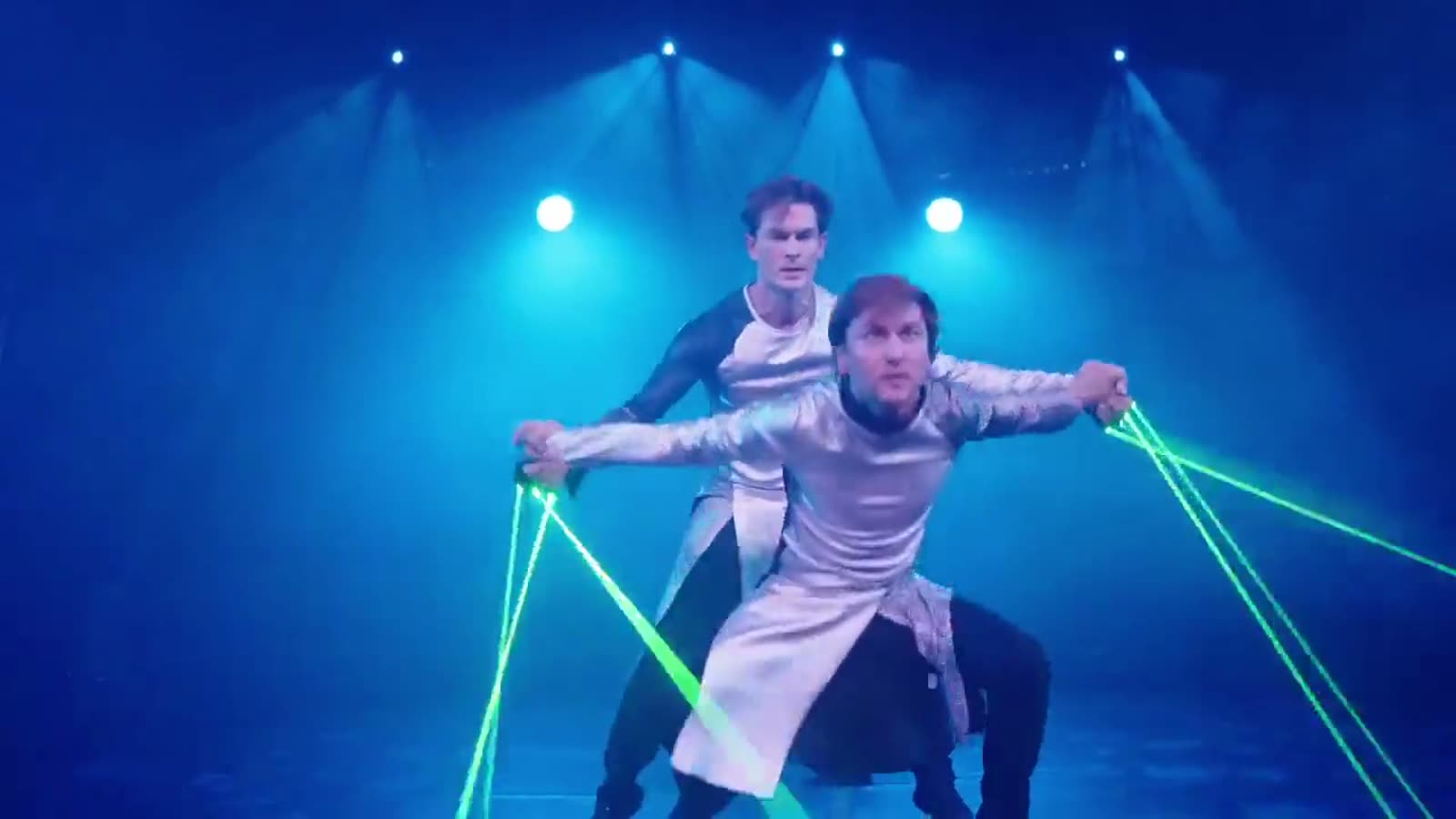 Jim & John in silver futuristic costumes, green laser beams running from their gloves into the blue-lit room